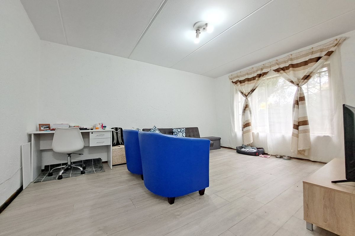 A living room featuring light-toned laminate flooring and textured walls, providing a neutral base for interior design.
