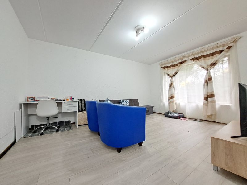 A living room featuring light-toned laminate flooring and textured walls, providing a neutral base for interior design.