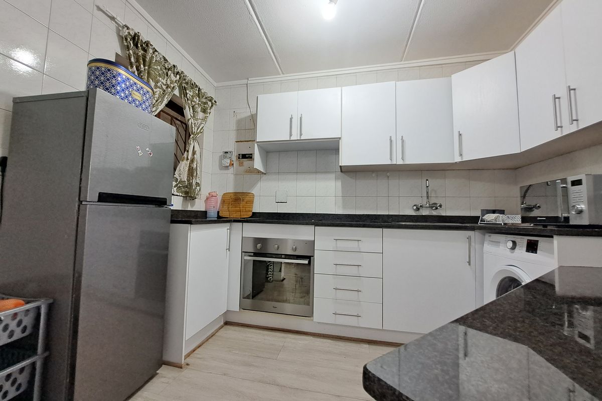 A functional kitchen featuring white cabinetry, dark laminate countertops, tiled backsplash, and built-in oven, providing a practical workspace for daily cooking.