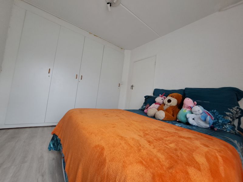 A bedroom featuring built-in cupboards and light-toned laminate flooring, providing functional storage space.