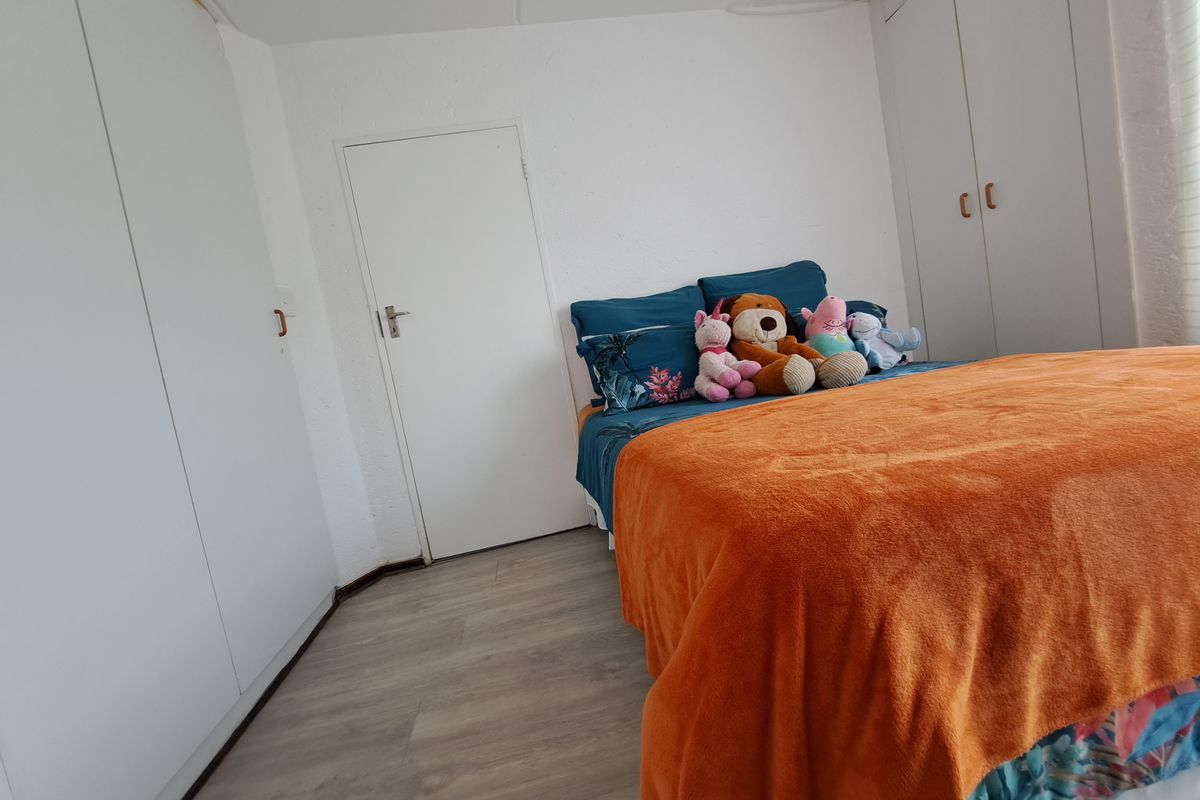 A bedroom featuring light-toned laminate flooring and ample built-in cupboard storage space.