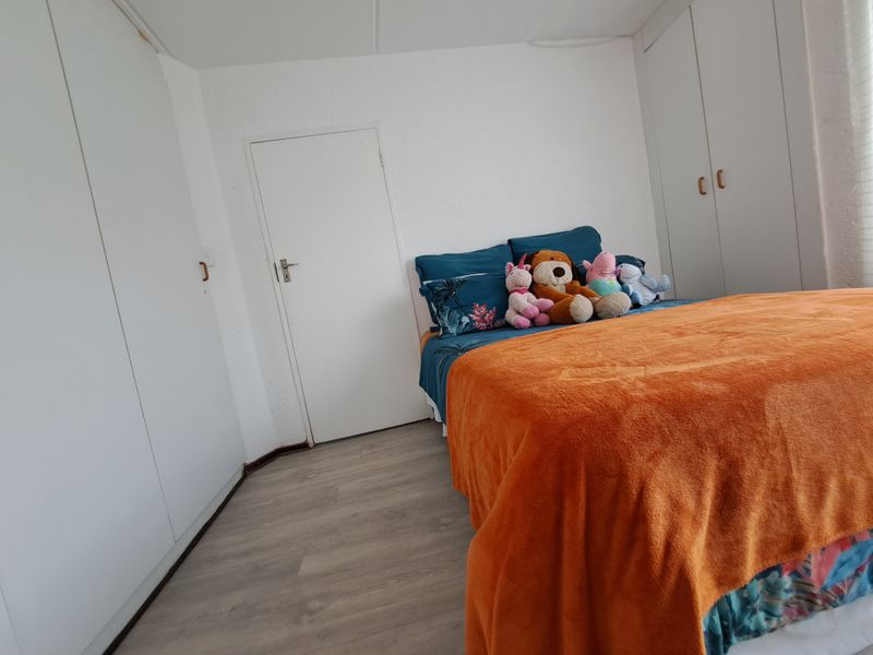 A bedroom featuring light-toned laminate flooring and ample built-in cupboard storage space.
