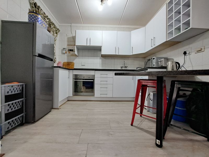 A functional kitchen featuring white cabinetry, built-in oven, tiled backsplash, and wood-look laminate flooring, providing a practical workspace for daily cooking.