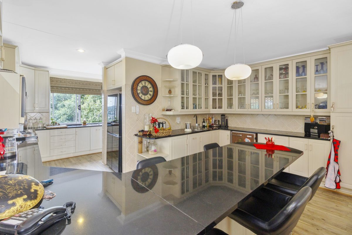 A well-appointed kitchen featuring granite countertops, extensive glass-front cabinetry, and a central island with breakfast bar seating, complemented by modern pendant lighting.