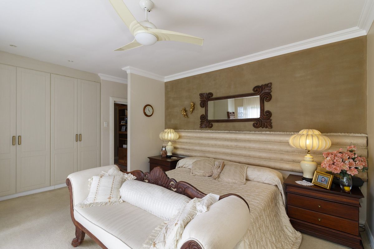 Spacious bedroom featuring built-in cupboards, a ceiling fan, and decorative coving, offering a comfortable and well-maintained living space.