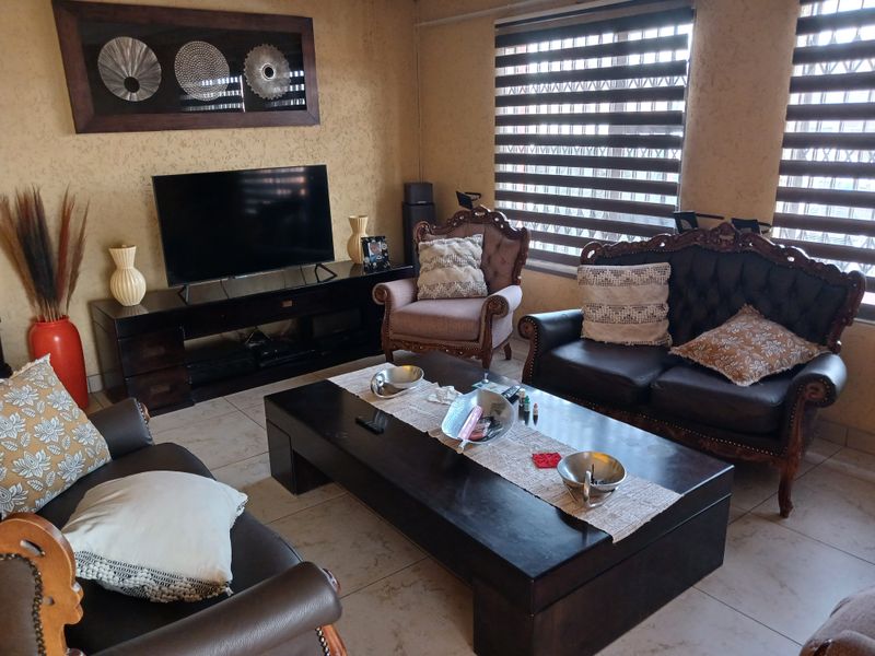 A comfortable living room featuring tiled flooring, large windows with modern zebra blinds, and integrated security bars for added peace of mind.