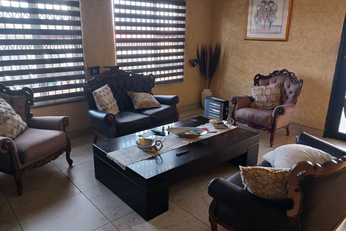 A comfortable living room featuring tiled flooring and modern dual-tone roller blinds, providing a functional and well-lit space for relaxation.
