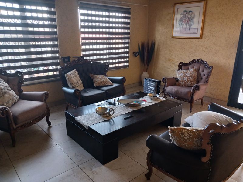 A comfortable living room featuring tiled flooring and modern dual-tone roller blinds, providing a functional and well-lit space for relaxation.