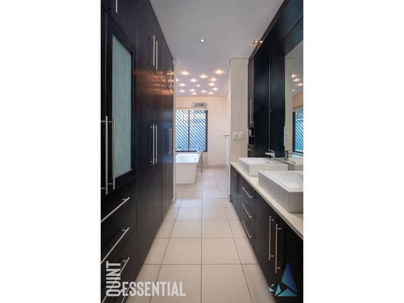 Modern bathroom featuring a double vanity with dark cabinetry, a freestanding bathtub, and elegant recessed ceiling lighting.