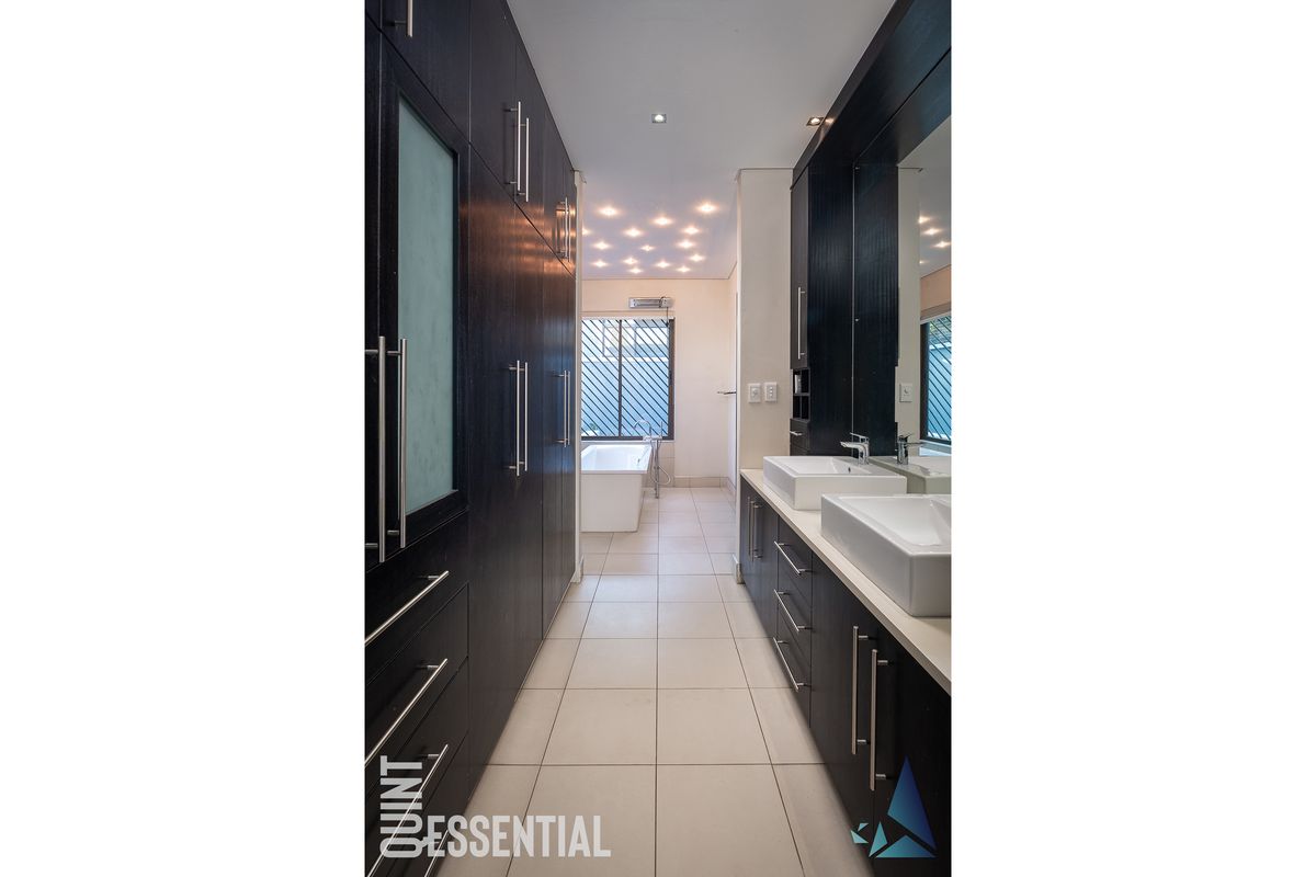 Modern bathroom featuring a double vanity with dark cabinetry, a freestanding bathtub, and elegant recessed ceiling lighting.