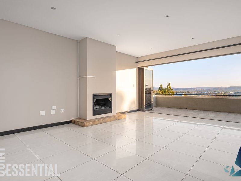 Spacious open-plan living area featuring large format floor tiles, a built-in fireplace, and seamless access to a balcony with expansive views.