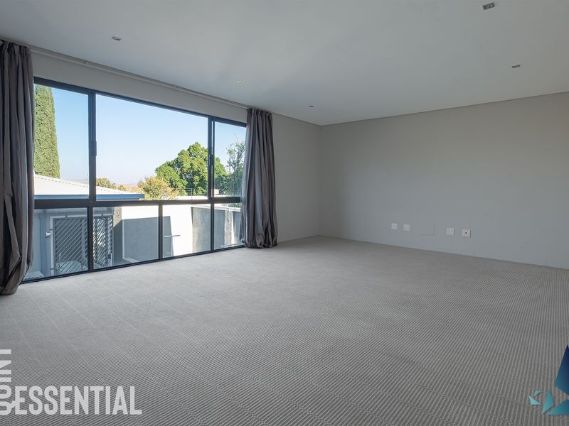 A spacious, empty bedroom featuring large windows with natural light, neutral wall finishes, and fitted carpeting.