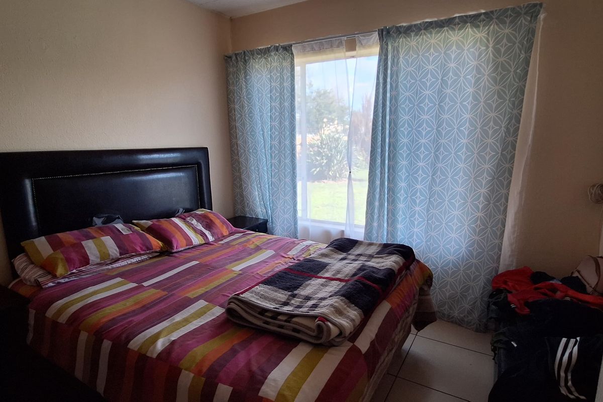A functional bedroom featuring tiled flooring and a large window that allows for natural light.