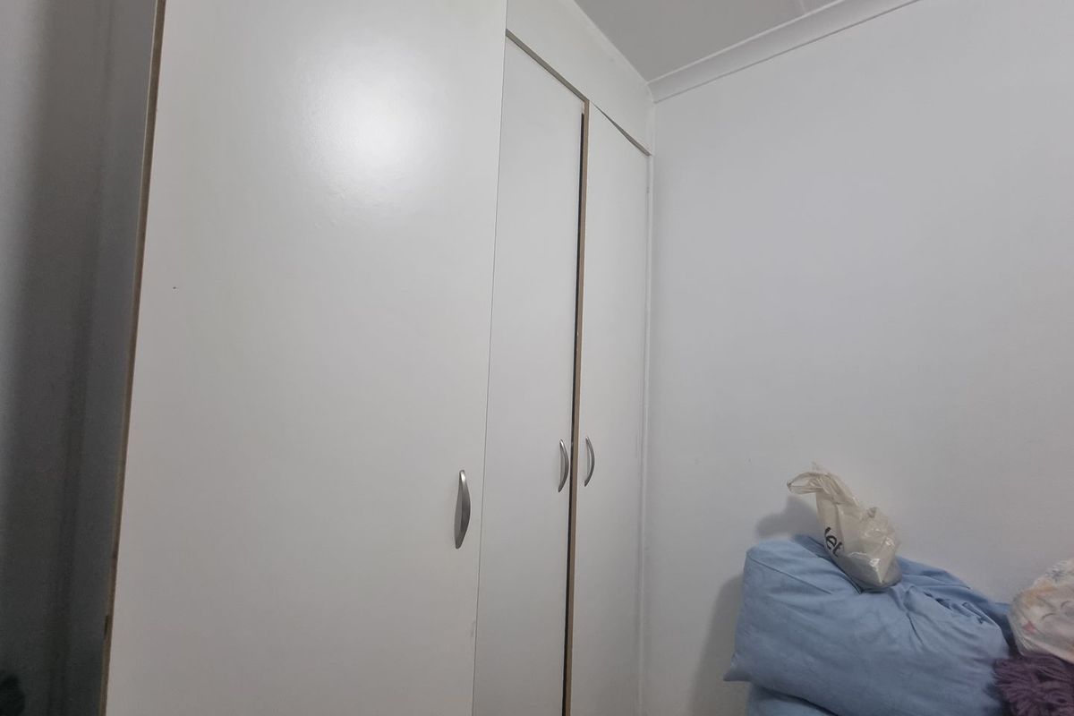 A bedroom featuring built-in white cabinetry with modern handles, providing ample storage space.
