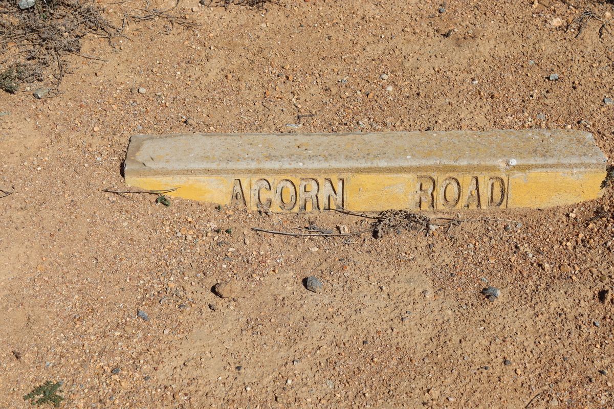 A concrete street name marker for Acorn Road situated on the ground at the property boundary.