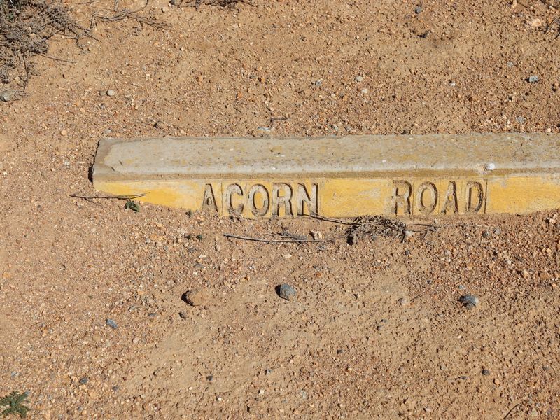 A concrete street name marker for Acorn Road situated on the ground at the property boundary.