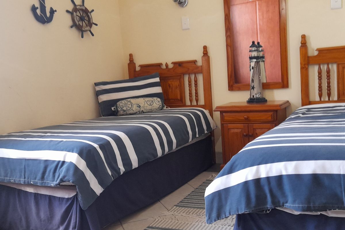A bedroom featuring tiled flooring and a built-in wall mirror, currently furnished with twin beds.