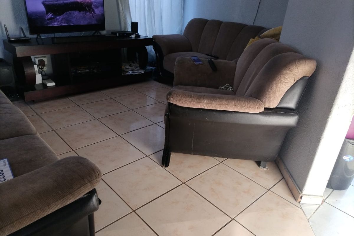 A living room area featuring ceramic floor tiles and neutral wall finishes, providing a functional space for relaxation.