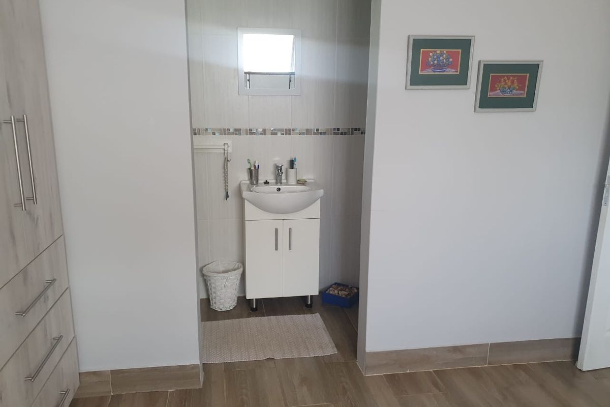 A functional bathroom vanity area featuring a modern basin, cabinet storage, and tiled splashback, integrated into a bedroom or dressing space.