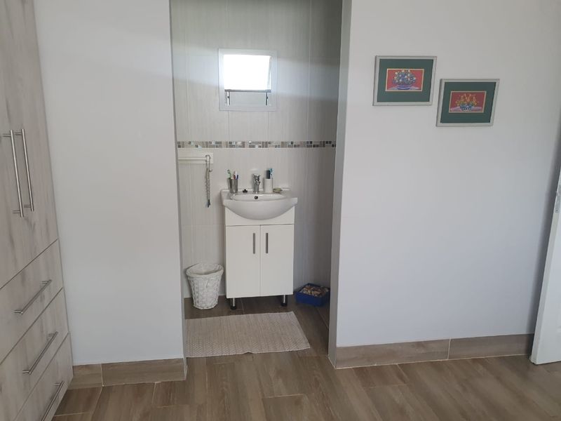 A functional bathroom vanity area featuring a modern basin, cabinet storage, and tiled splashback, integrated into a bedroom or dressing space.