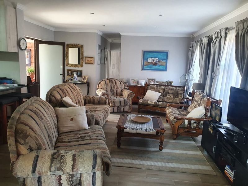 A spacious living room featuring tiled flooring, recessed downlighting, and decorative cornicing, offering a comfortable and functional layout for relaxation.