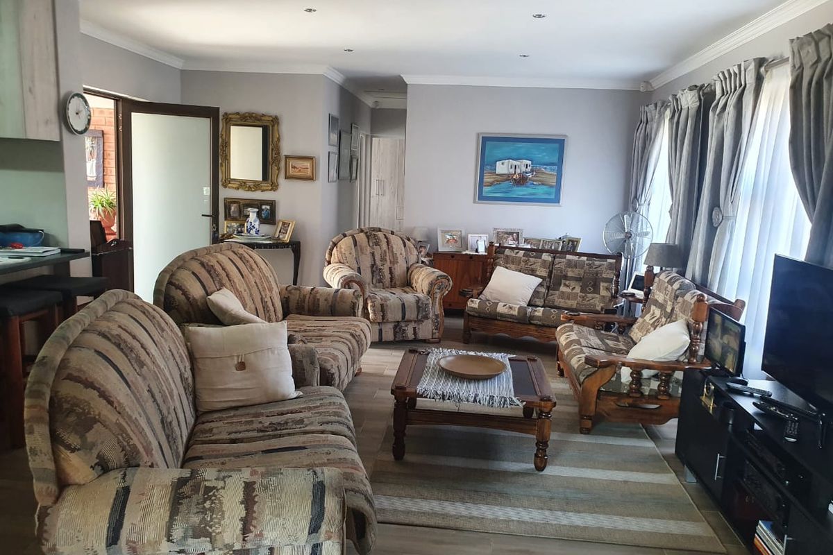 A spacious living room featuring tiled flooring, recessed downlighting, and decorative cornicing, offering a comfortable and functional layout for relaxation.