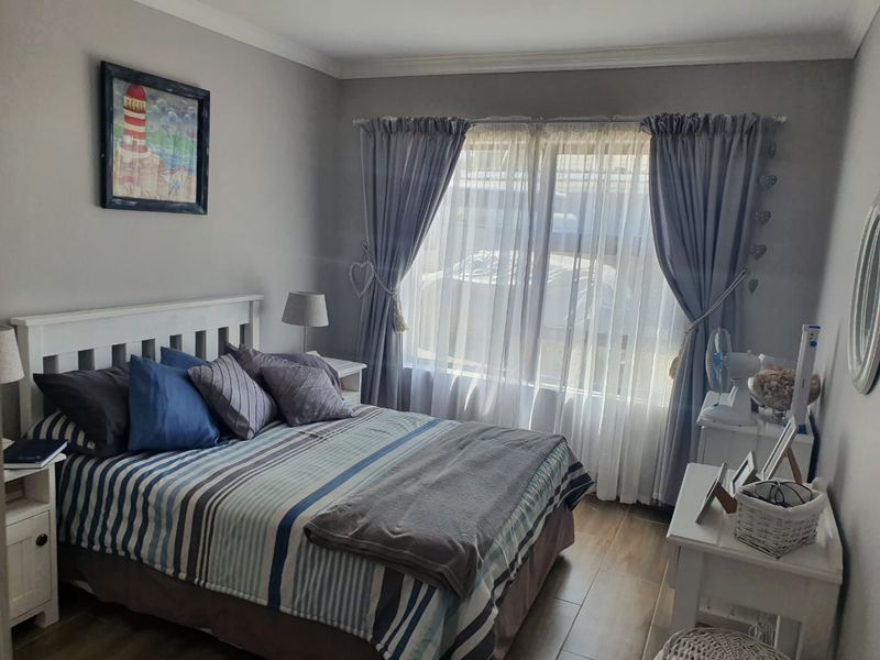 A well-maintained bedroom featuring neutral wall tones, tiled flooring, and classic cove cornicing, offering a comfortable and functional living space.