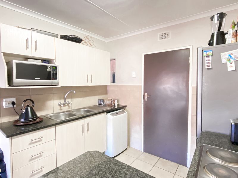 Functional kitchen featuring light-toned cabinetry, dark granite-look countertops, tiled backsplash, and integrated appliances, providing a practical workspace for daily cooking.