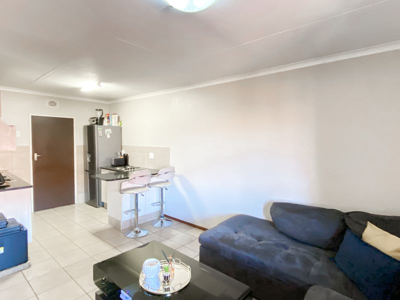 Open plan living area featuring a compact kitchen with breakfast bar and tiled flooring, seamlessly connecting to the main living space.