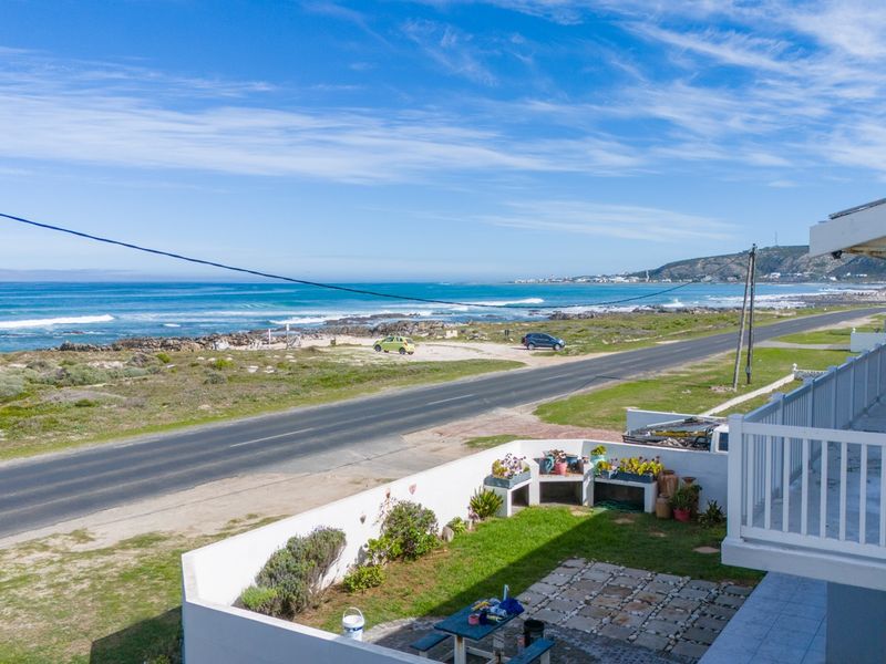 Elevated coastal view featuring a balcony overlooking a private garden with a built-in braai area and direct proximity to the ocean.