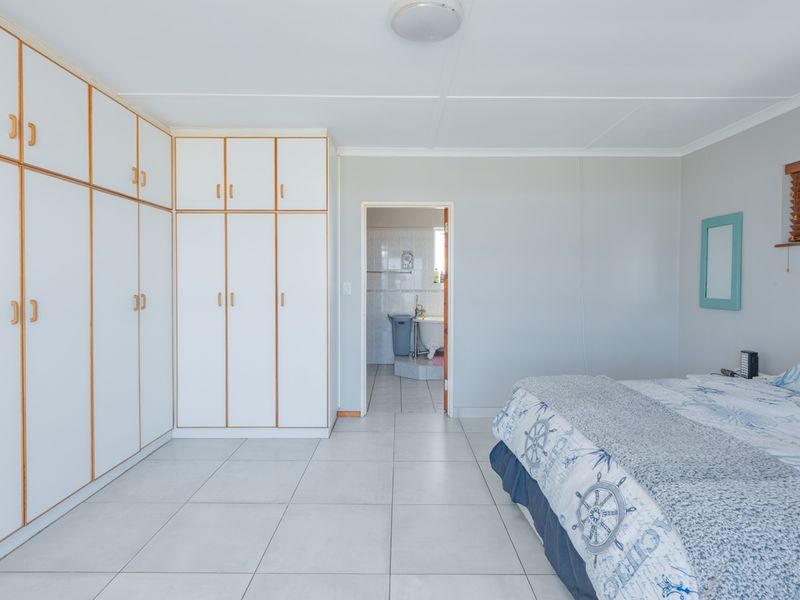 A bedroom featuring extensive built-in white cabinetry, neutral tiled flooring, and direct access to an adjoining bathroom.
