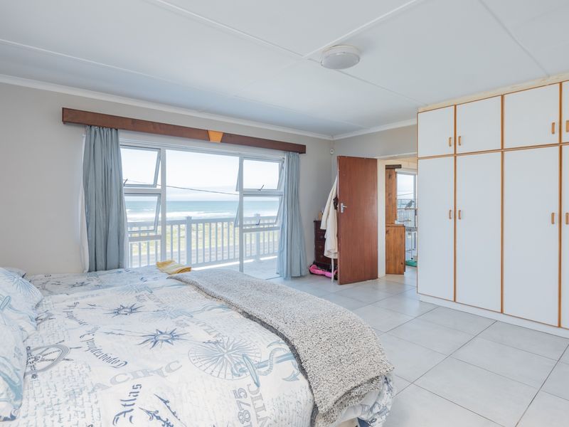 Spacious bedroom featuring built-in cupboards, tiled flooring, and a sliding glass door providing direct access to a balcony with ocean views.