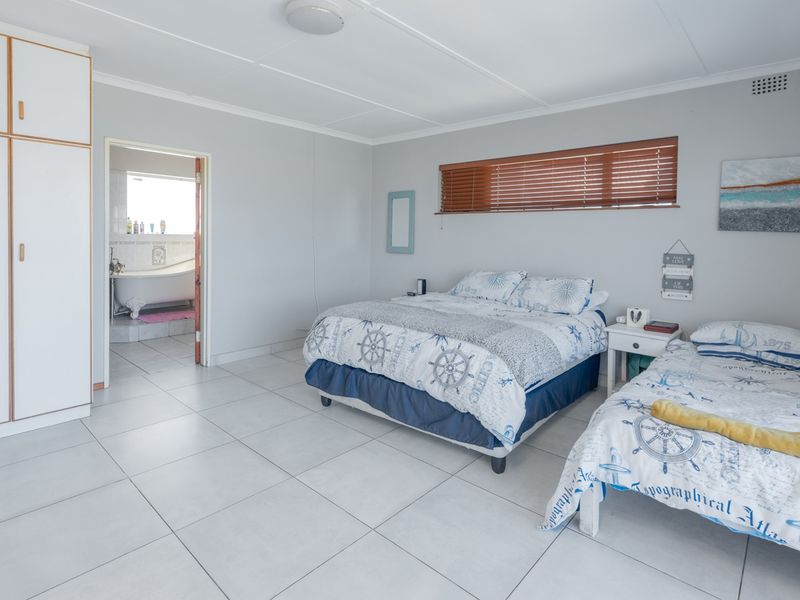 Spacious bedroom featuring tiled flooring, built-in cupboards, and direct access to an en-suite bathroom with a bathtub.