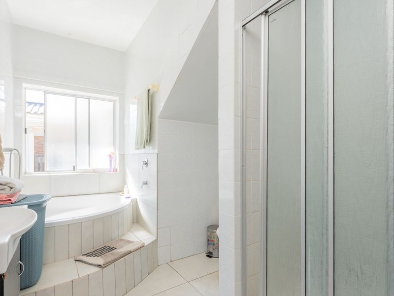 A functional bathroom featuring a built-in bathtub, separate shower enclosure, and pedestal basin with tiled finishes throughout.