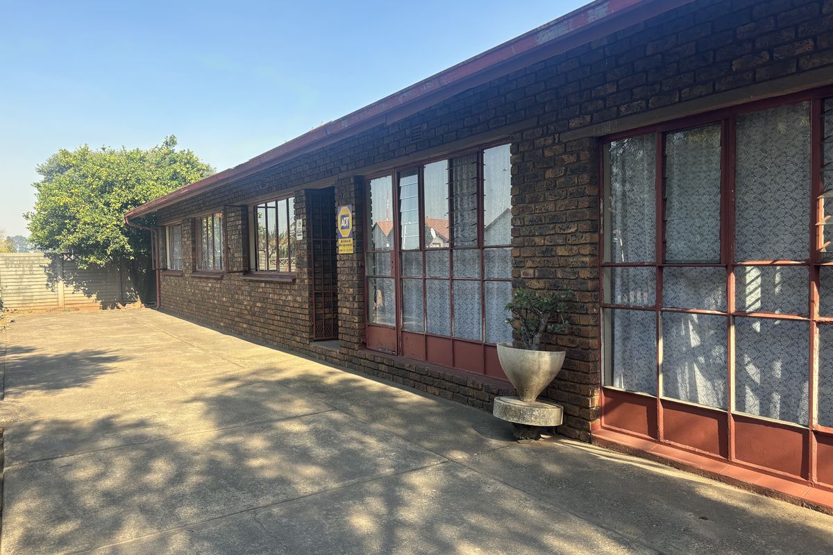 Rear exterior view of the property featuring a face brick facade, steel-framed windows, and a concrete patio area.