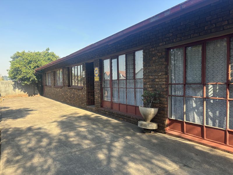 Rear exterior view of the property featuring a face brick facade, steel-framed windows, and a concrete patio area.
