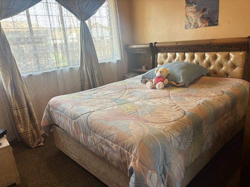 A bedroom featuring a window with curtains and carpeted flooring.