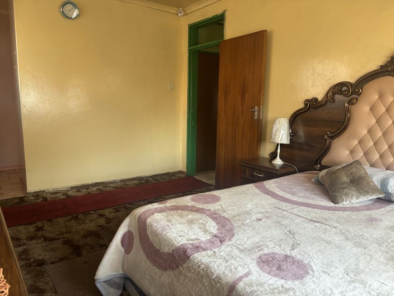 A bedroom featuring dated wall finishes and worn carpeting, offering potential for modernization and aesthetic improvement.