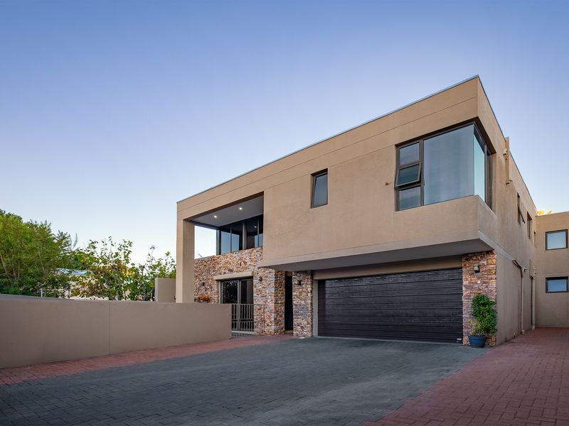 Modern double-story residence featuring stone cladding, a spacious paved driveway, and an integrated double garage with a clean, contemporary architectural design.