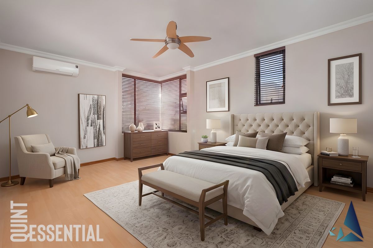 A well-appointed bedroom featuring a ceiling fan, split-system air conditioning, and large windows with venetian blinds, finished with light laminate flooring.