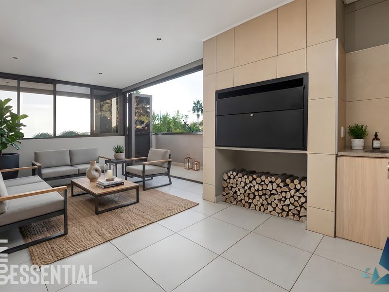 A modern covered patio featuring a built-in fireplace, tiled flooring, and a convenient kitchenette area with a sink and cabinetry.