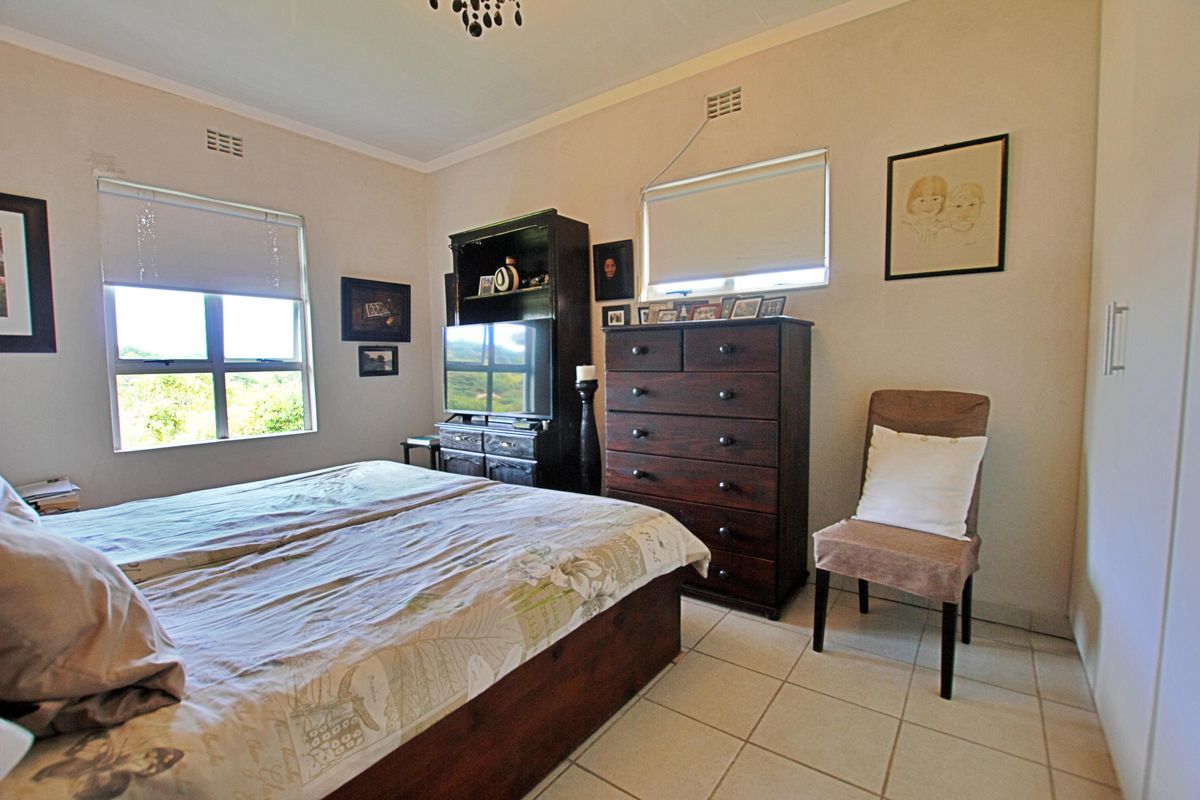 A functional bedroom featuring tiled flooring, built-in cupboards, and dual windows with roller blinds, offering a practical and well-lit living space.