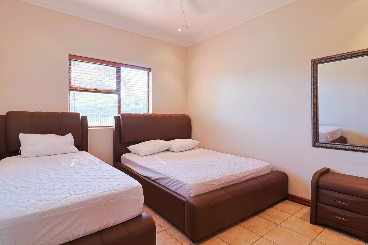 A bedroom featuring tiled flooring, a ceiling fan, and a window with fitted blinds.