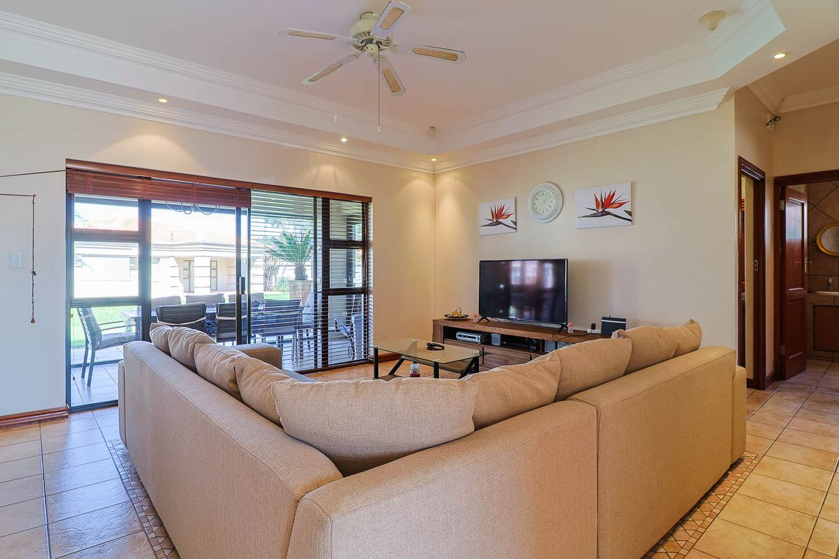 Spacious living room featuring a tray ceiling, recessed lighting, ceiling fan, and large sliding glass doors providing direct access to the outdoor patio area.