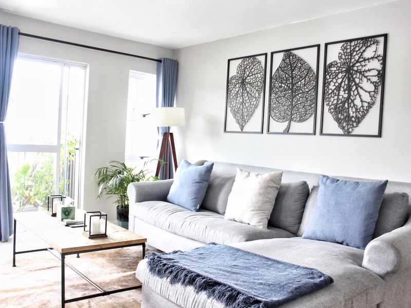 A bright and well-maintained living room featuring tiled flooring and a large sliding glass door providing access to the outdoor area.