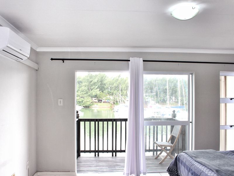 Bedroom featuring an air conditioning unit and a sliding glass door that opens onto a balcony with water views.