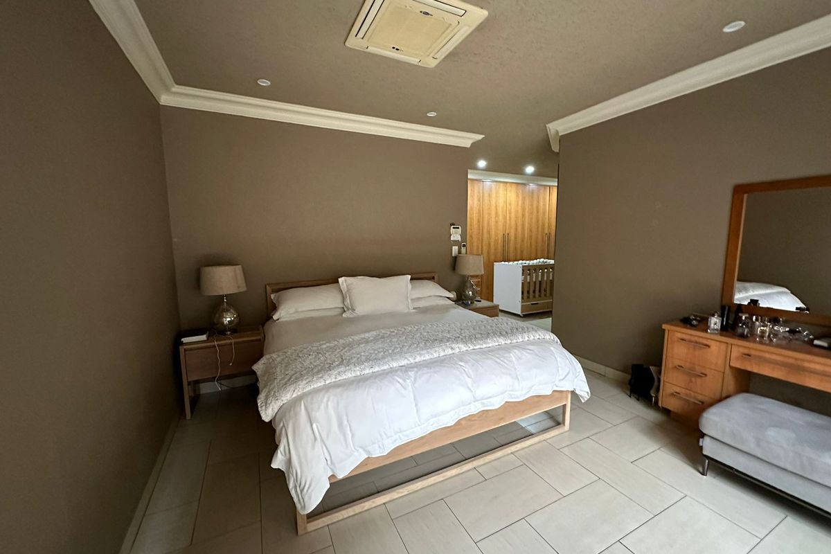 Spacious bedroom featuring tiled flooring, crown molding, recessed lighting, a ceiling-mounted air conditioning unit, and integrated wooden built-in cupboards.