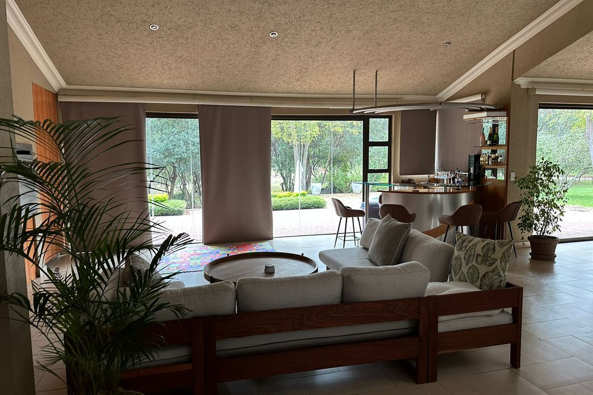 Spacious living room featuring a vaulted ceiling, recessed lighting, built-in bar area, and large sliding glass doors opening to the garden.