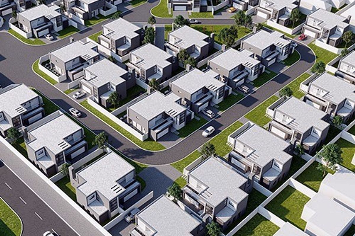 An aerial view of a modern residential estate featuring uniform housing units, paved streets, and landscaped garden plots.