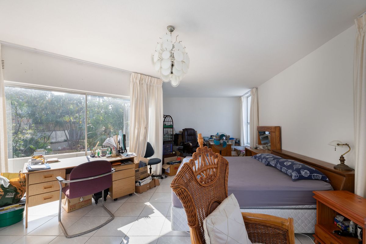 Spacious bedroom featuring large sliding windows that provide ample natural light and views of the garden area.